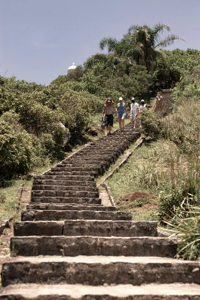 Grupo subindo uma escadaria de pedra no meio da mata na Ilha do Mel