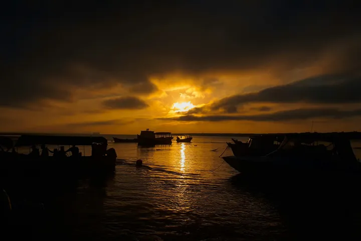 Barco de madeira na água ao pôr do sol na Ilha do Mel